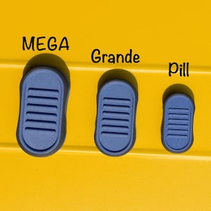 May include: Three blue pill-shaped objects with a ridged design are displayed against a yellow background. The objects are labeled "MEGA", "Grande", and "Pill" in black text, indicating different sizes.