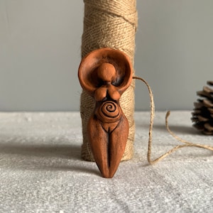 Pregnant ceramic mother goddess. Clay female figure. Amulet of fertility.