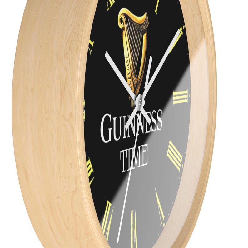 Puede incluir: Un reloj con marco de madera, esfera negra y marcadores de hora con n&uacute;meros romanos blancos. La esfera del reloj presenta un logotipo de arpa Guinness dorado con el texto "ESTD 1778" y "GUINNESS TIME".