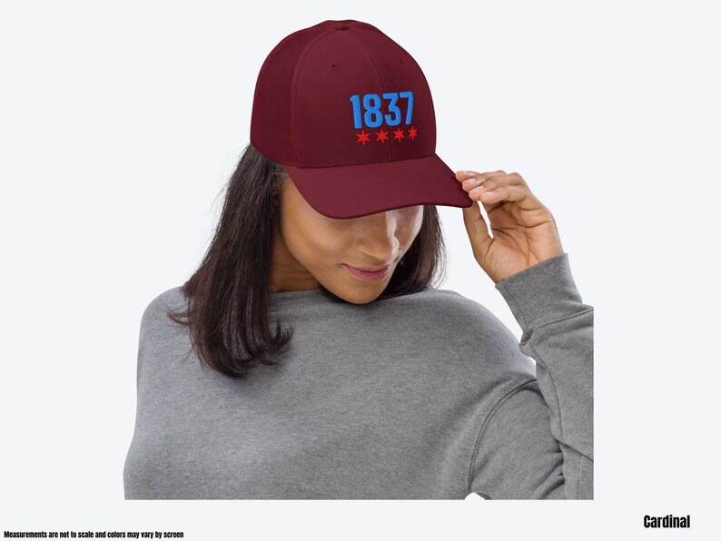 May include: A maroon baseball cap with a blue embroidered "1837" and red stars. The cap is worn by a person with long brown hair.
