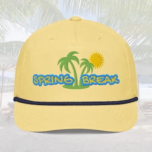 May include: A yellow baseball cap with a navy blue brim. The cap has an embroidered design of palm trees, a sun, and the text "SPRING BREAK".