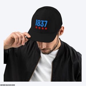May include: A black baseball cap with the number "1837" embroidered in blue and five red stars below it.