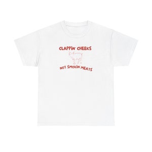 May include: White t-shirt with red text that says "Clappin' Cheeks Not Smokin' Meats" and a cartoon pig illustration.