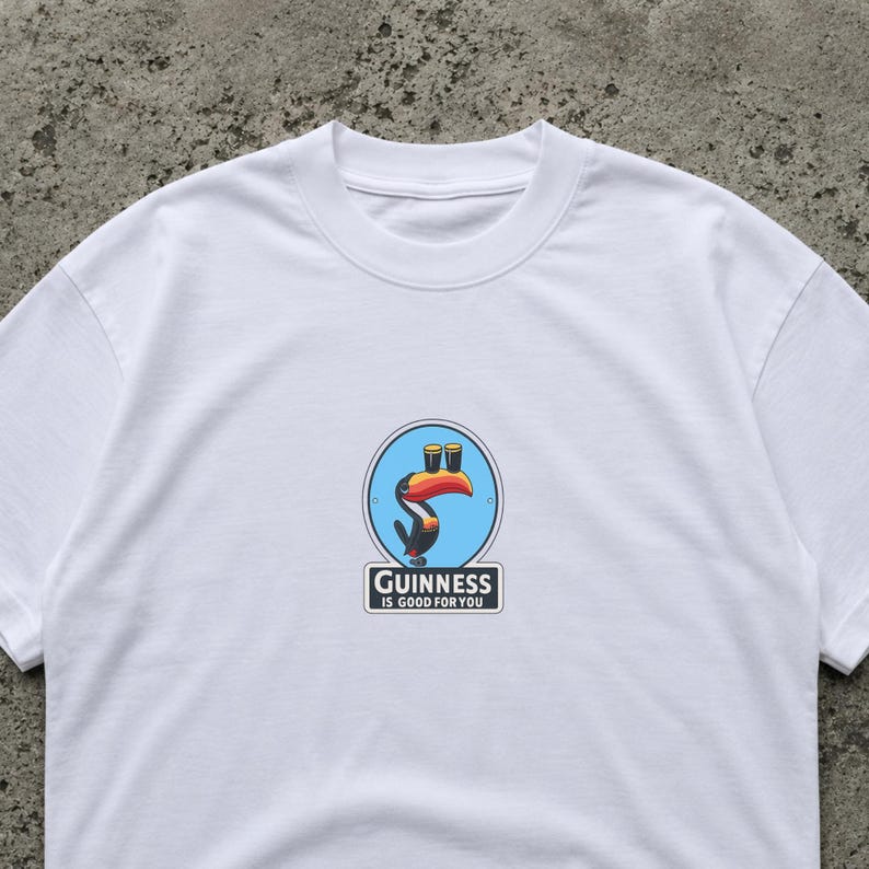 May include: White t-shirt featuring a colorful Guinness logo with a toucan and two pints of beer. The text "Guinness is good for you" is printed below the logo. The shirt is made of a soft material.