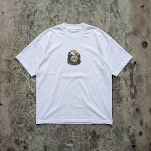 May include: White t-shirt featuring a graphic of a crushed Guinness beer can. The can is black, gold, and silver, with the Guinness logo visible. The shirt has short sleeves and a crew neck.
