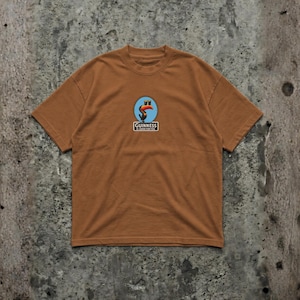 K&ouml;nnte beinhalten: Ein braunes T-Shirt mit einem kreisf&ouml;rmigen Logo, das einen Tukan, einen blauen Hintergrund und den Text "Guinness" in einem wei&szlig;en Rechteck zeigt. Das T-Shirt hat kurze &Auml;rmel und einen Rundhalsausschnitt.