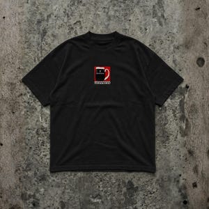 May include: Black t-shirt featuring the Guinness logo. The logo is a red square with a white and black design of a pint of Guinness, with the word "Guinness" below it in white text.