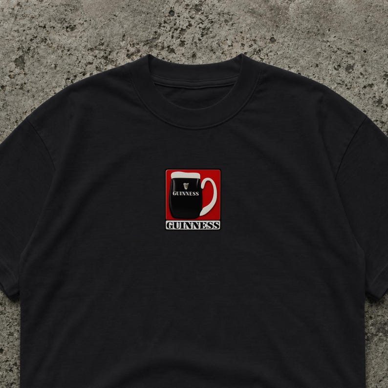 May include: Black t-shirt featuring a graphic of a pint of Guinness stout in a red square. The pint is black with a white head, and the handle is white. The word "GUINNESS" is printed below the pint in white.