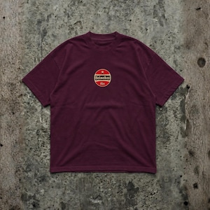 Pu&ograve; includere: T-shirt bordeaux con scollo tondo. La maglietta presenta un logo circolare sul petto con le parole "Heineken" e "bier" in rosso, oro e bianco. La maglietta &egrave; realizzata in materiale morbido.