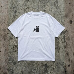 May include: White t-shirt featuring a black graphic of a pint of Guinness with a running figure. The Guinness logo is visible at the top of the pint. The shirt is made of a soft, comfortable material.
