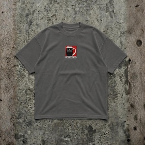 May include: A gray t-shirt featuring a small embroidered design of a Guinness pint glass. The design includes the Guinness logo in red, black, and white. The shirt has short sleeves and a crew neck.