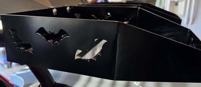 Puede incluir: Un organizador de metal negro con recortes en forma de murci&eacute;lago. El organizador tiene forma rectangular con m&uacute;ltiples compartimentos. Los recortes de murci&eacute;lago est&aacute;n espaciados uniformemente en la parte delantera, agregando un toque decorativo.