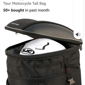 Puede incluir: Bolsa trasera para moto negra Nelson Rigg CL-1060-ST2 Tour con un casco de moto blanco en el interior. La bolsa tiene una cremallera superior y cierres de hebilla. Dise&ntilde;ada para uso en moto.