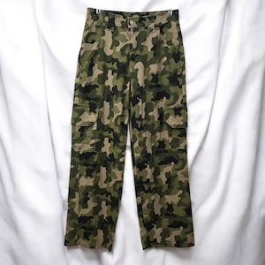 May include: Camouflage cargo pants in shades of green, brown, and black. The pants feature multiple pockets, a button closure, and a straight leg design. The fabric has a military-inspired pattern.