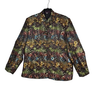 May include: A long-sleeved jacket with a black background and a colorful floral pattern in shades of gold, green, blue, and red. The jacket has a mandarin collar and is buttoned down the front. The jacket is hanging on a black hanger.