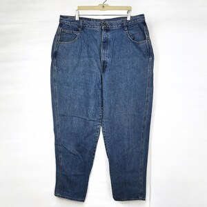 May include: Blue denim jeans hanging on a hanger. The jeans have a classic five-pocket design, a button and zipper closure, and a relaxed fit. The denim has a medium wash with subtle fading.