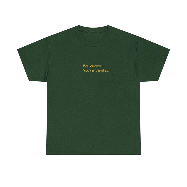 K&ouml;nnte beinhalten: Ein dunkelgr&uuml;nes T-Shirt mit dem goldenen Text "Be Where You're Wanted". Das T-Shirt hat einen Rundhalsausschnitt und ist aus einem weichen Stoff gefertigt. Der Text ist mittig auf der Brust platziert.