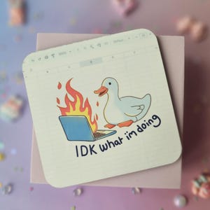 Puede incluir: Un pato blanco con llamas naranjas saliendo de una computadora portátil, sobre un fondo blanco con el texto "IDK what I'm doing".