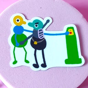 May include: A die-cut sticker featuring a yellow-headed blue and green creature standing next to a teal creature with a dark body and backpack. The teal creature reaches out to touch a tall green post with a yellow and red button on its top surface.