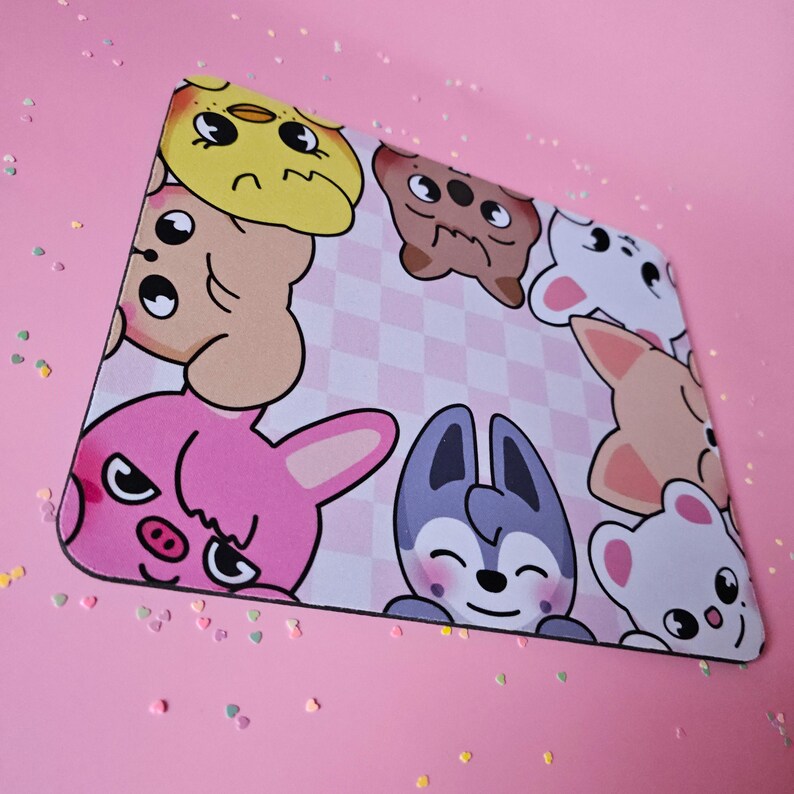 May include: A pink and white mouse mat with a checkered pattern. The mouse mat features cartoon animals, including a pink bunny, a grey wolf, a brown bear, a white dog, and a yellow chick.