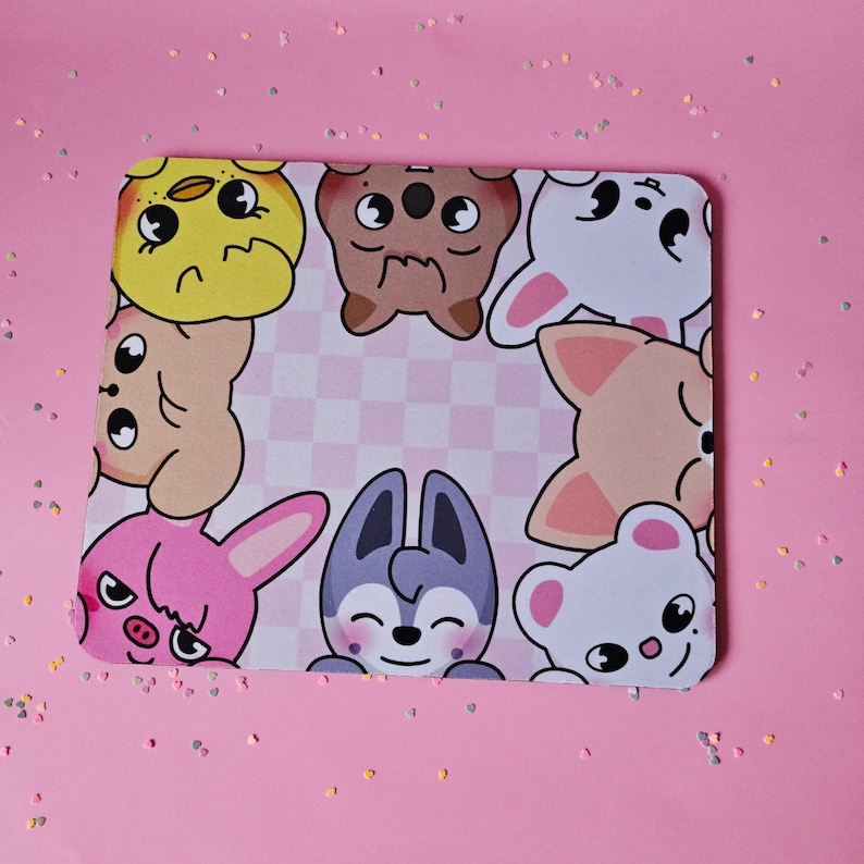 May include: A pink and white checkered mouse mat with cartoon animal faces around the border. The animals include a yellow chick, a brown bear, a white bunny, a pink bunny, a grey wolf, a brown dog, and a white bear.