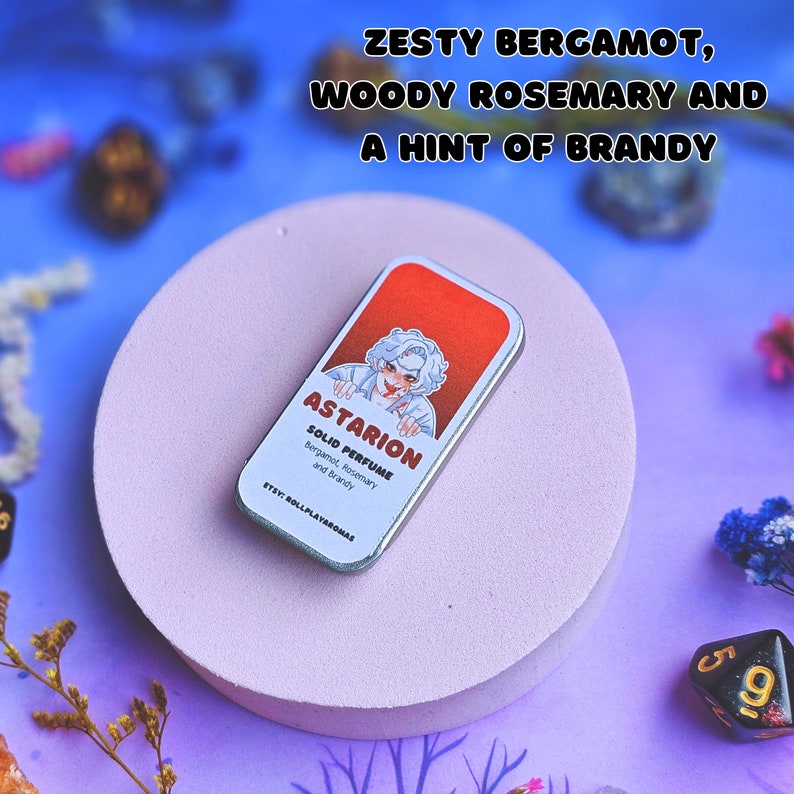 K&ouml;nnte beinhalten: Eine silberne Dose mit einer Cartoon-Illustration einer Person mit wei&szlig;en Haaren und roten Augen. Die Dose ist mit "Astarion Solid Perfume Bergamot, Rosemary and Brandy" und "Etsy: RollPlayAromas" beschriftet.