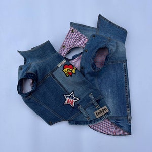 May include: Two denim vests with red and white checkered lining. One vest has a red heart with "LOVE" embroidered on it and a star with the American flag on it. The other vest has a "Doggytail" label.