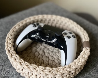 May include: A beige crocheted bowl with a white and black video game controller inside.