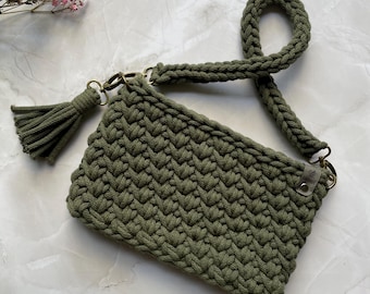 May include: A green crocheted crossbody bag with a tassel. The bag has a long strap and a metal clasp.