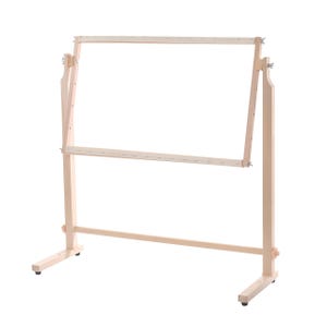 Könnte beinhalten: Ein heller Stickrahmen aus Holz mit Standfuß, bestehend aus einem verstellbaren rechteckigen Rahmen auf zwei vertikalen Stützen mit einer horizontalen Basisstange und Metallflügelmuttern zur Fixierung der Stoffspannung und des Winkels.