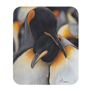 以下が含まれることがあります： 2羽の皇帝ペンギンが寄り添っているクローズアップ。手前のペンギンは奥のペンギンの翼の下に頭を突っ込んでいる。両方のペンギンは黒と白の羽を持ち、目の周りにオレンジ色の模様がある。