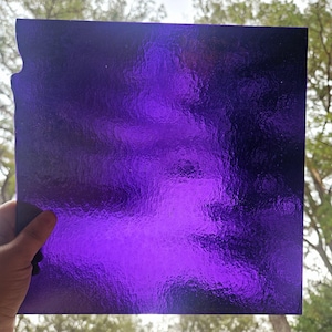 May include: A sheet of textured purple glass. The glass has a rippled, uneven surface.