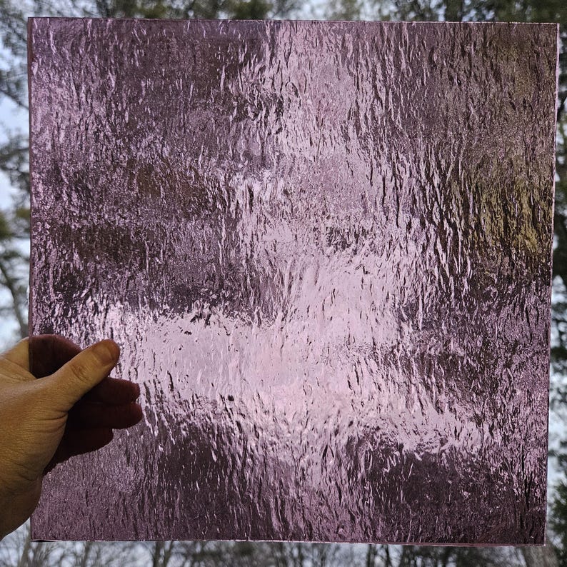 May include: A sheet of textured glass with a light purple hue. The glass has a rippled, wave-like pattern.