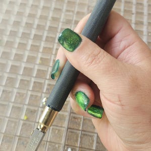 May include: A close-up of a glass cutter with a black handle and a gold tip. The cutter is labeled "JAPAN TC-10".