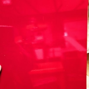 May include: A solid red sheet of paper with a glossy finish.