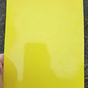 May include: A bright yellow sheet of paper. The paper has a glossy finish.
