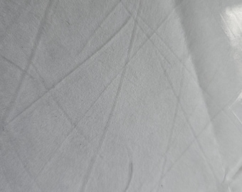 May include: A close-up shot of a white fabric with subtle diagonal and curved lines. The fabric appears to be smooth and possibly made of a lightweight material. The lighting creates soft shadows and highlights.