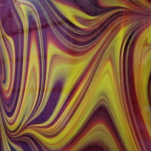 May include: Abstract glass art with a swirling pattern of yellow, purple, and red hues. The colors blend and flow, creating a dynamic and visually appealing design. The glass appears to have a glossy finish.