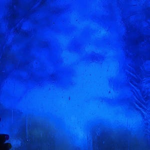 May include: A vibrant, deep blue stained glass panel. The glass has a textured appearance with swirling patterns, creating a dynamic visual effect. The color is a rich, saturated blue, reminiscent of the ocean.