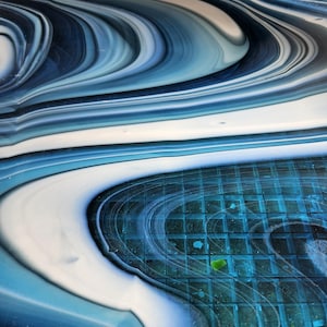 May include: Abstract art piece with swirling patterns in shades of blue, white, and gray. The design resembles flowing water or marble, with a textured appearance. The artwork has a modern and artistic aesthetic.