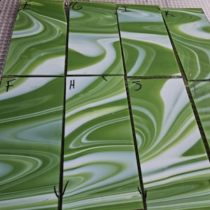 May include: Ten rectangular glass tiles with a green and white marbled pattern. The tiles are labeled with letters from E to L.