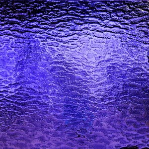 May include: A close-up of a textured, abstract background with a gradient of purple and blue hues. The surface has a rippled, wavy pattern, creating a dynamic and visually interesting effect.