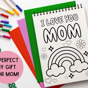 May include: A white coloring book with a black and white illustration of a rainbow, clouds, and flowers. The text "I Love You Mom" is written in large, bold letters at the top of the page.
