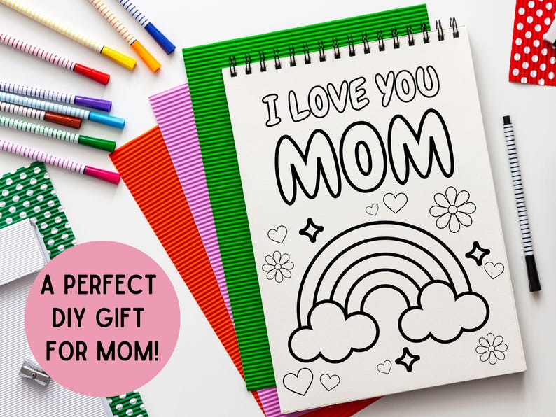 May include: A white coloring book with a black and white illustration of a rainbow, clouds, and flowers. The text "I Love You Mom" is written in large, bold letters at the top of the page.