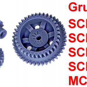 May include: Three blue plastic gears, one large, one medium, and one small. The large gear has a central hub with four spokes and a small hole in the centre. The text "Grundig SCF6000 SCF6100 SCF6200 SCF40 MCF400" is visible in red text.