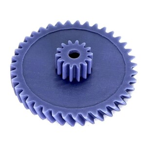 May include: A close-up of two interlocking blue gears. The larger gear has a toothed outer edge and a flat center. A smaller gear sits on top, also with teeth. The gears are set against a white background.