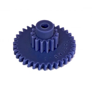 Può includere: Un ingranaggio in plastica blu con un ingranaggio più piccolo al centro. L'ingranaggio più grande ha 32 denti e l'ingranaggio più piccolo ha 12 denti. L'ingranaggio è etichettato "M25A".