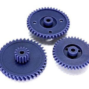 May include: Three blue plastic gears of different sizes. The gears have a smooth, rounded surface and are designed to interlock.