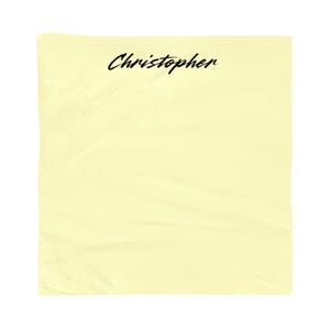 Op de afbeelding: Een lichtgele stof met de naam "Christopher" in zwarte cursieve letters.