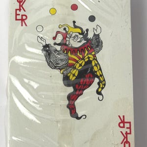 May include: A deck of playing cards in plastic wrap. The Joker card features a colorful jester juggling three balls. The word "JOKER" is printed in red on the left side of the card.